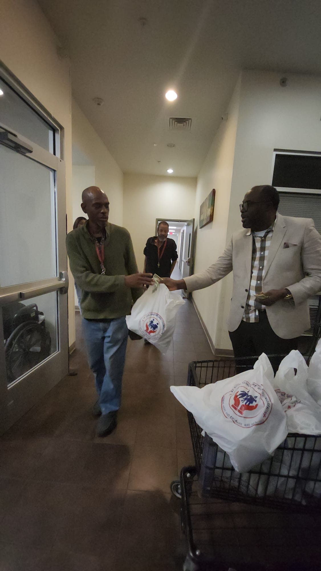 Food distribution in Houston - volunteer handing ICOBGF branded bag to community member